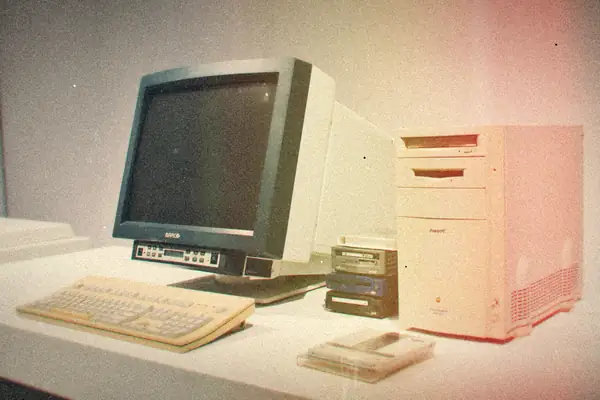 A beige desktop computer tower with a CRT monitor and keyboard on a white desk.