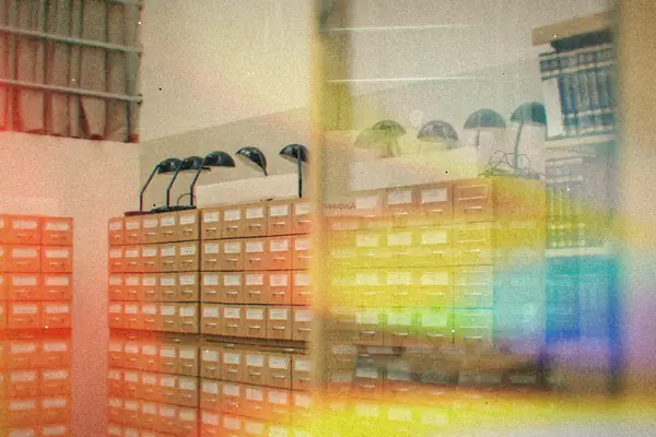 Rows of wooden library card catalog drawers under desk lamps.