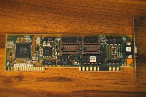 An old expansion card with chips and gold contacts lying on a wooden table.