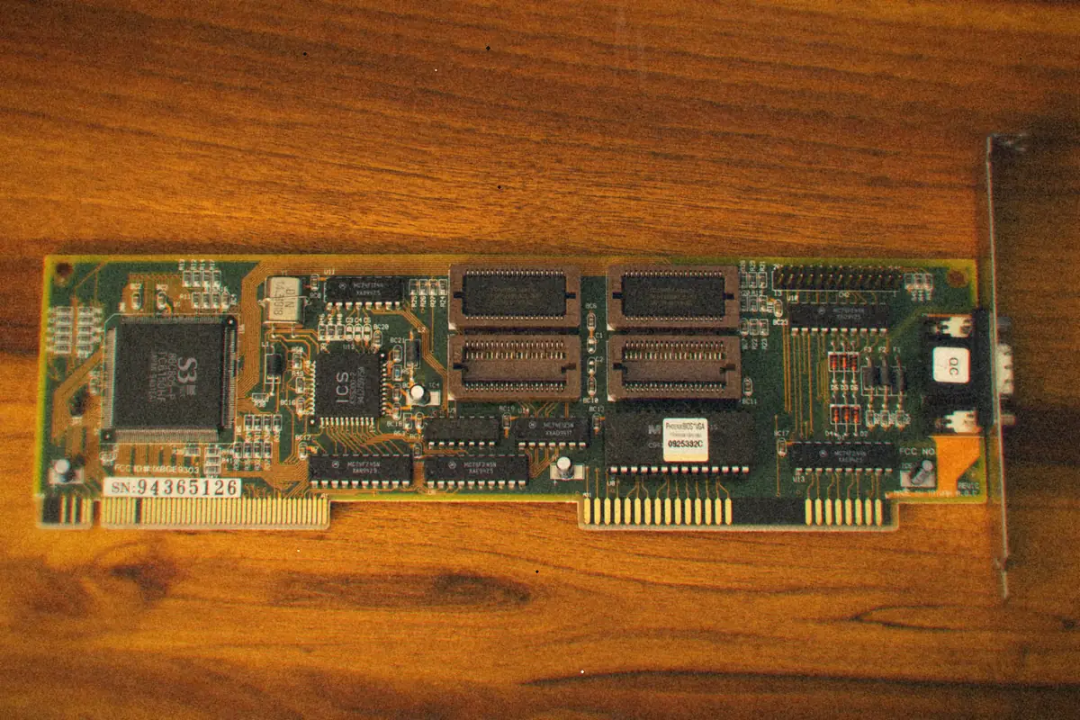An old expansion card with chips and gold contacts lying on a wooden table.