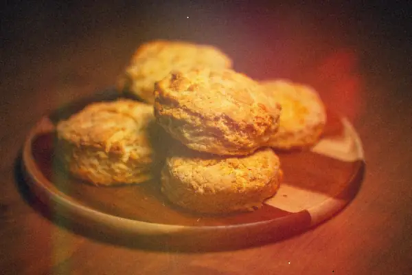 Golden baked biscuits stacked on a wooden plate.