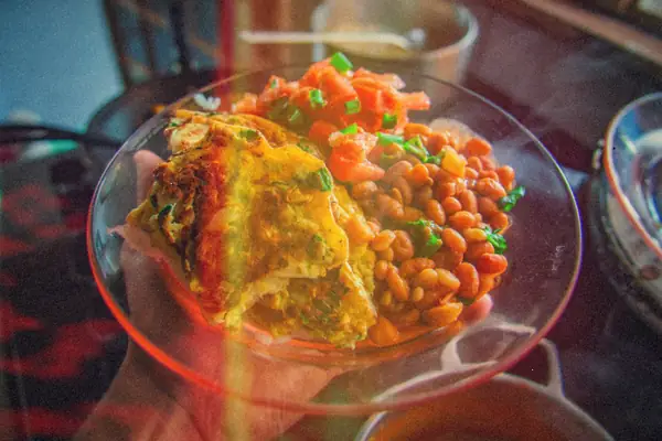 A plate holding an omelet with baked beans and fresh salsa.
