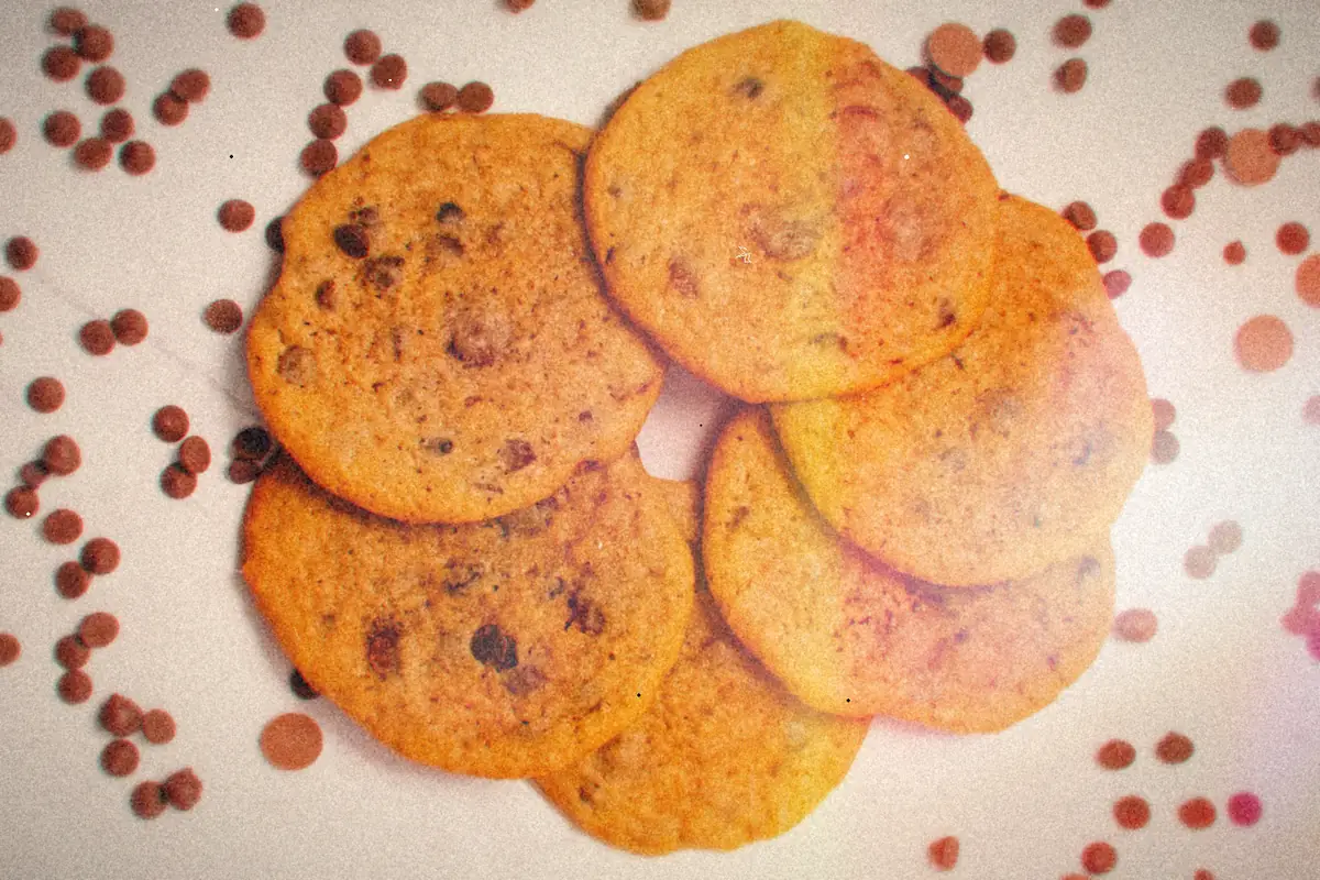 A ring of chocolate chip cookies on a white surface scattered with chocolate chips.