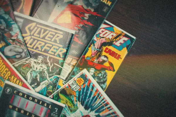 A spread of 1990s comic books fanned out across a dark wooden floor.