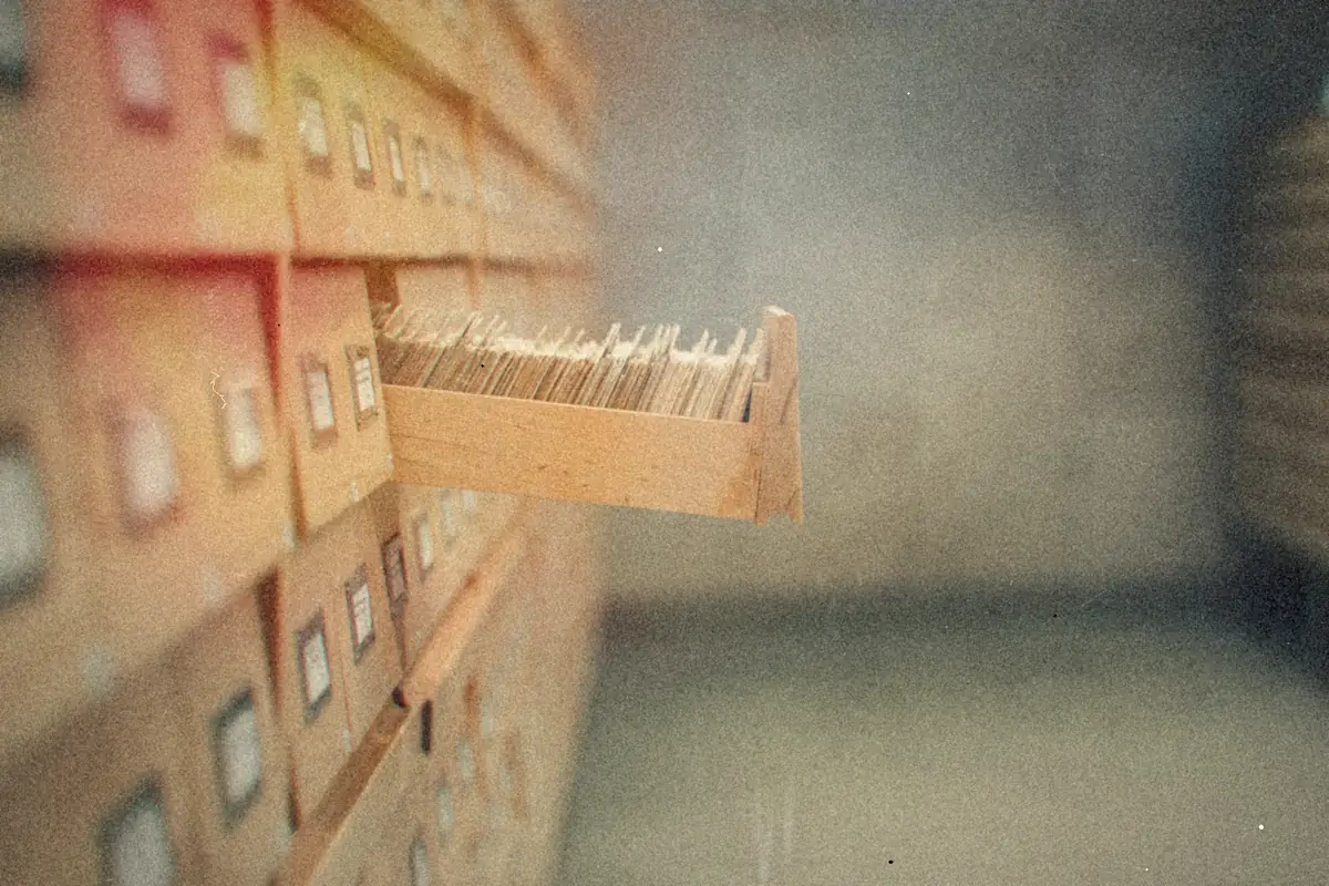 A drawer of index cards pulled out from a wall of wooden card catalog drawers.