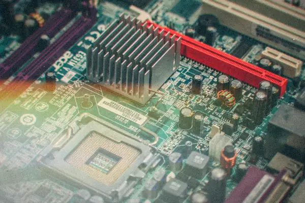 A computer motherboard with an empty CPU socket, heatsink and red expansion slot.