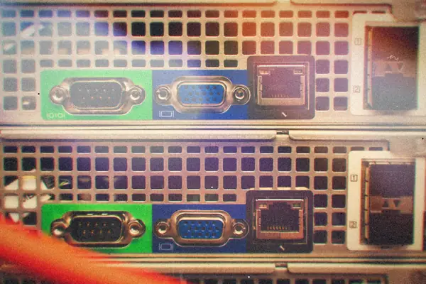 Serial, VGA and network ports on the back of stacked server units with a red cable running past.
