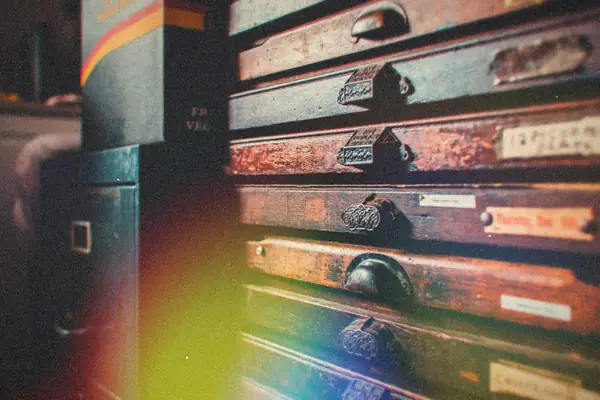 A weathered wooden cabinet of thin labeled drawers in a workshop.