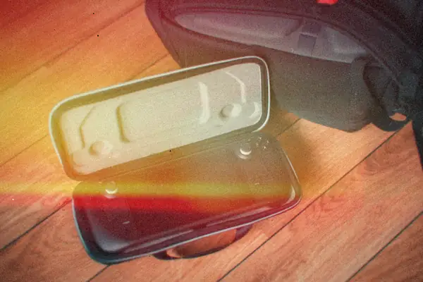 A Steam Deck handheld in its open carrying case on a wooden floor beside a black backpack.