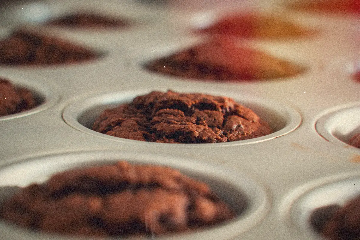 Chocolate muffins cooling in a metal muffin pan.
