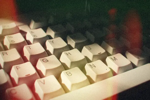 Keys of a computer keyboard caught in hard light against a dark background.