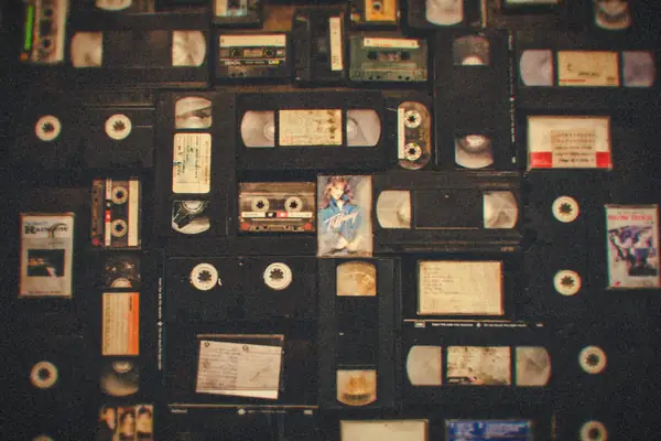 An overhead spread of dozens of assorted VHS tapes and audio cassettes.