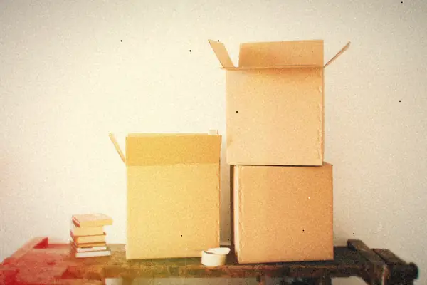 Stacked cardboard boxes and a few books on a weathered wooden table.