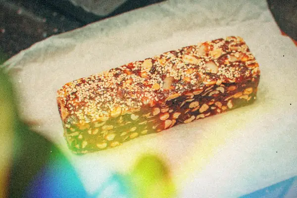 A homemade nut and sesame seed protein bar on parchment paper.