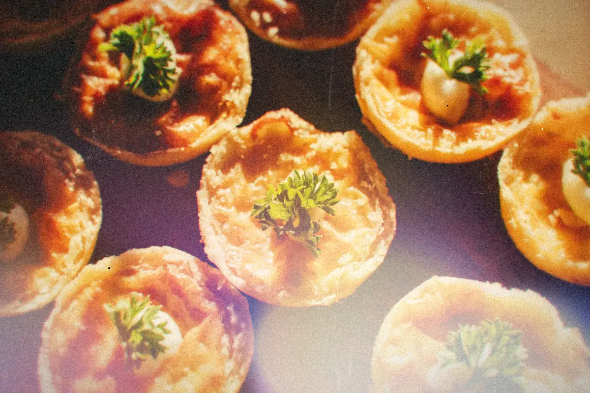 Small baked egg and cheese cups topped with parsley on a wooden board.