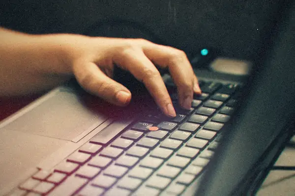 A hand typing on a black ThinkPad keyboard with its red TrackPoint nub.