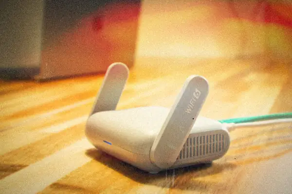 A Wi-Fi router with antennas on a wooden desk.