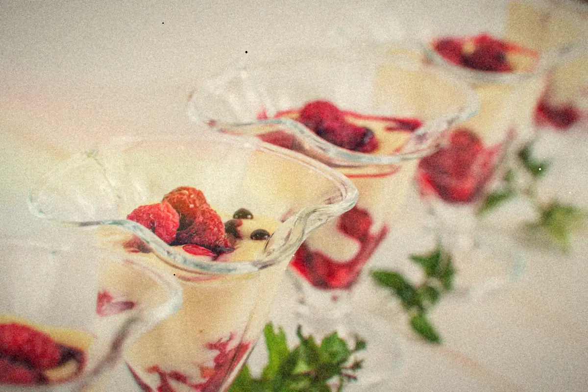 Glass dessert cups of creamy pudding layered with raspberry sauce and topped with fresh raspberries.
