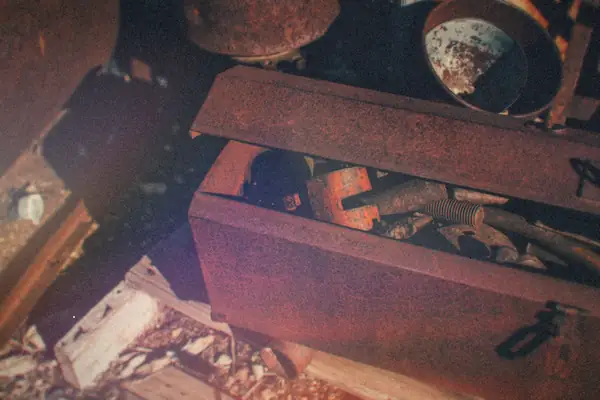 An old rusty toolbox full of worn hand tools sitting in the sun.