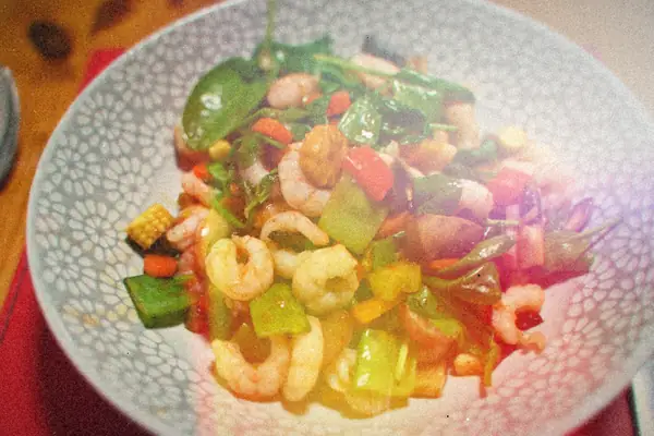 Shrimp stir fry with spinach, peppers, baby corn and mushrooms in a patterned bowl.