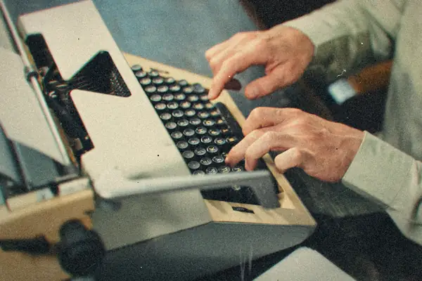 Hands typing on a vintage typewriter in an office.