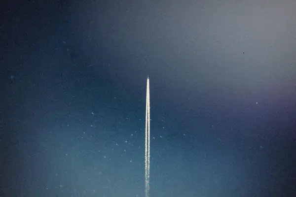 A rocket's trail streaking straight up through a starry night sky.