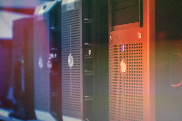 A row of desktop PC towers lined up side by side under blue and red light.