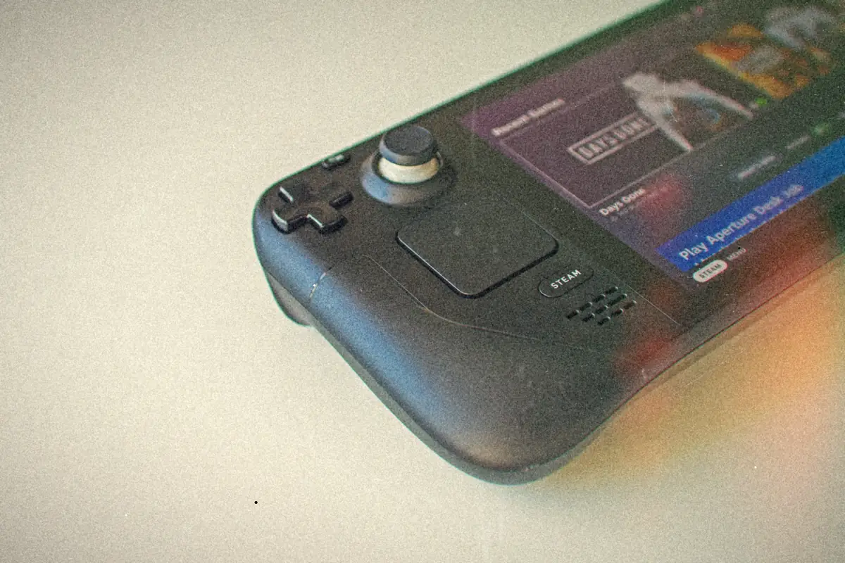 A retro game console with cartridges and a VHS tape spread on a wooden floor.