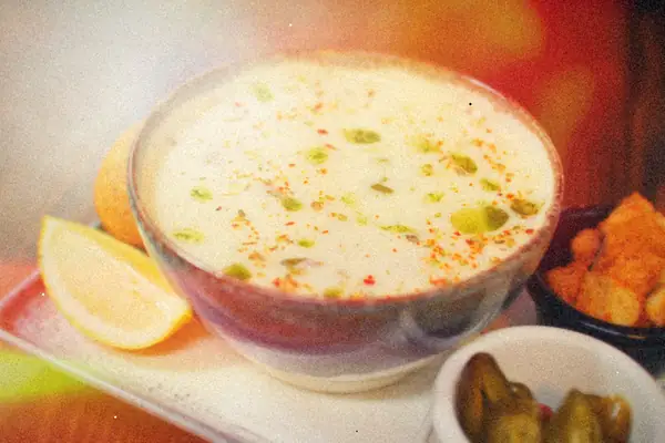 A bowl of creamy white soup flecked with green chiles and spices, served with lemon, croutons and pickled jalapenos.